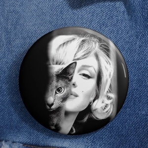 May include: A black and white photo of a woman with blonde hair and a cat. The woman's face is partially obscured by the cat's head. The cat's eye is looking directly at the viewer.