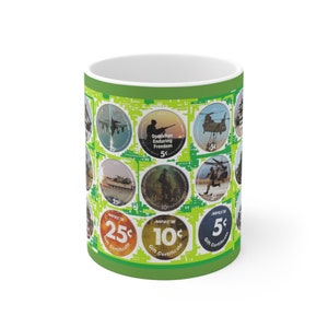 Pode incluir: Uma caneca de cerâmica branca com um design verde e amarelo. O design apresenta veículos militares, soldados e helicópteros. A caneca tem três certificados de presente de 5 cêntimos, 10 cêntimos e 25 cêntimos.
