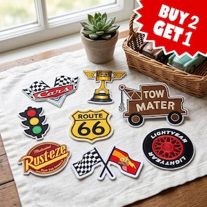 May include: A collection of embroidered patches featuring designs from the movie Cars, including a checkered flag, Piston Cup trophy, Tow Mater truck, traffic light, Route 66 sign, Rust-eze logo, Lightyear tire, and crossed racing flags.