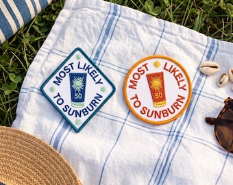Könnte beinhalten: Zwei gestickte Aufnäher mit dem Text MOST LIKELY TO SUNBURN. Einer ist rautenförmig mit blauem Rand und einem blauen Sonnencreme-Symbol. Der andere ist kreisförmig mit orangefarbenem Rand und einem orangefarbenen Sonnencreme-Symbol.