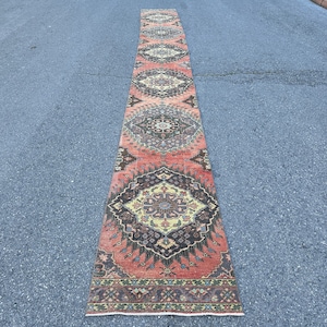 May include: A long, narrow rug with a traditional Persian design. The rug has a red, orange, and cream color scheme with intricate floral and geometric patterns.