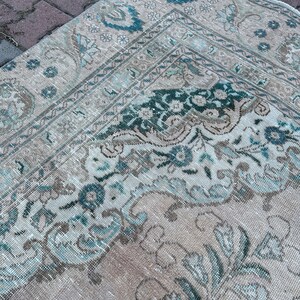 Puede incluir: Una alfombra vintage con un patr&oacute;n floral descolorido en tonos beige, azul y verde. La alfombra tiene un aspecto desgastado y est&aacute; hecha de un material suave y tejido.