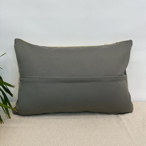 May include: A rectangular throw cushion featuring a solid dark grey fabric front with a horizontal seam across the middle. The cushion has a visible light-coloured, textured woven fabric border along the top and sides, creating a distinct contrast.