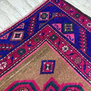 May include: A vintage Turkish rug with a geometric pattern in shades of pink, blue, and brown. The rug has a fringed edge and is woven with intricate details.
