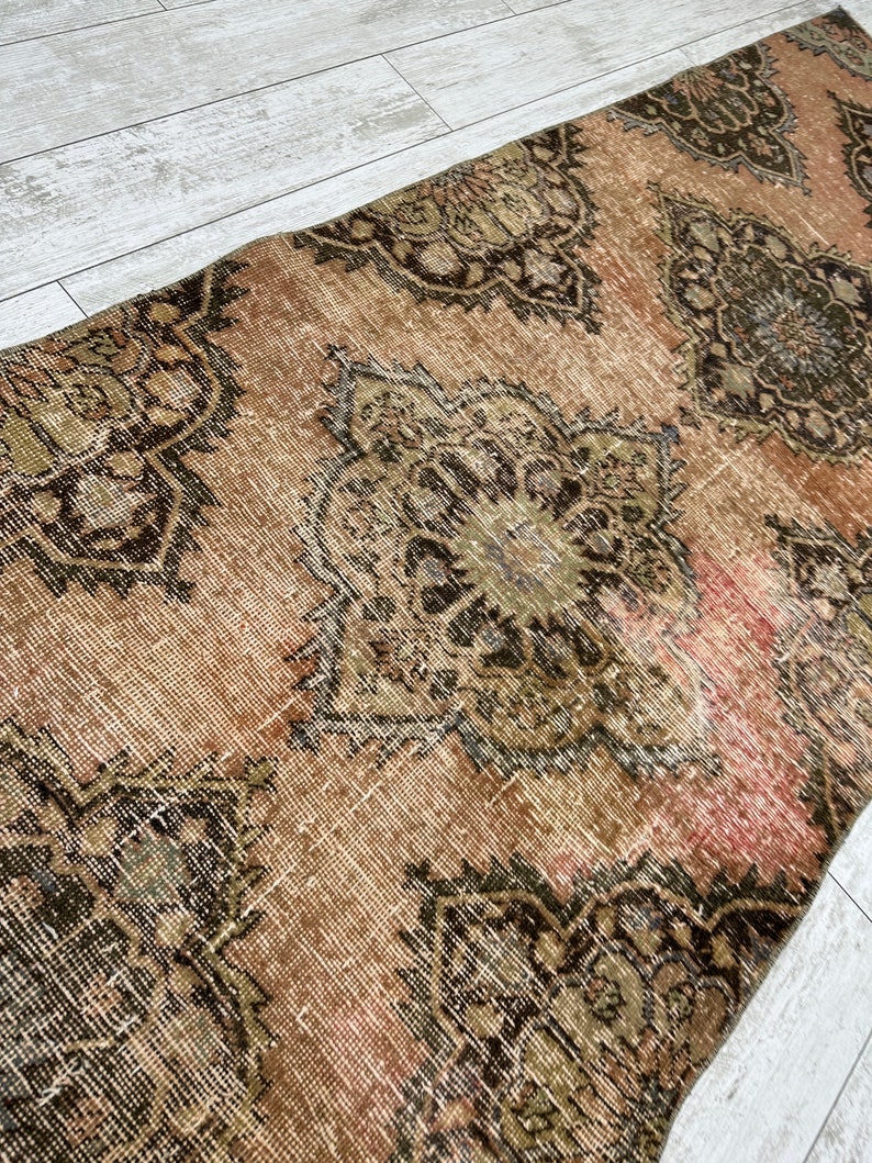 Puede incluir: Una alfombra vintage con un esquema de color rosa y marr&oacute;n descolorido. La alfombra tiene un dise&ntilde;o persa tradicional con intrincados patrones florales.
