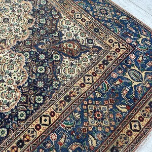 May include: A vintage Persian rug with a blue, cream, and red color scheme. The rug features intricate floral and geometric patterns.
