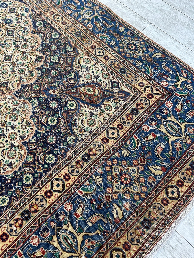 May include: A vintage Persian rug with a blue, cream, and red color scheme. The rug features intricate floral and geometric patterns.