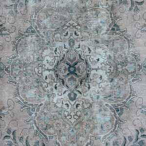Puede incluir: Una alfombra vintage con un patr&oacute;n floral descolorido en tonos azules, marrones y blancos. La alfombra tiene un aspecto desgastado y una textura desgastada.