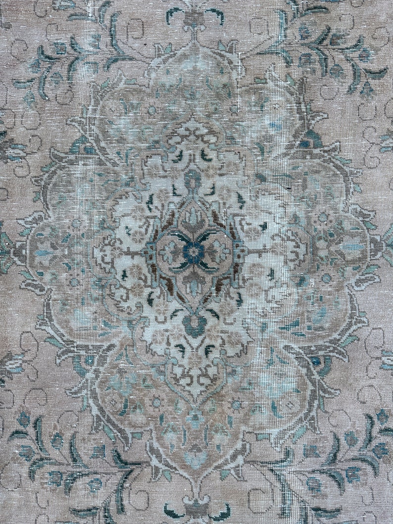 Puede incluir: Una alfombra vintage con un patr&oacute;n floral descolorido en tonos azules, marrones y blancos. La alfombra tiene un aspecto desgastado y una textura desgastada.