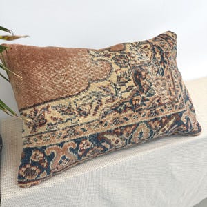 Peut inclure: Coussin rectangulaire avec un motif de tapis vintage. Le coussin présente un mélange de couleurs, notamment du marron, du beige et du bleu marine. Le motif présente des motifs complexes et un aspect texturé, ajoutant une touche d'élégance à tout espace.