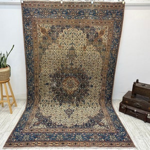 May include: A vintage Persian rug with a cream-colored center and a blue, red, and brown border. The rug has a floral pattern and is in good condition.