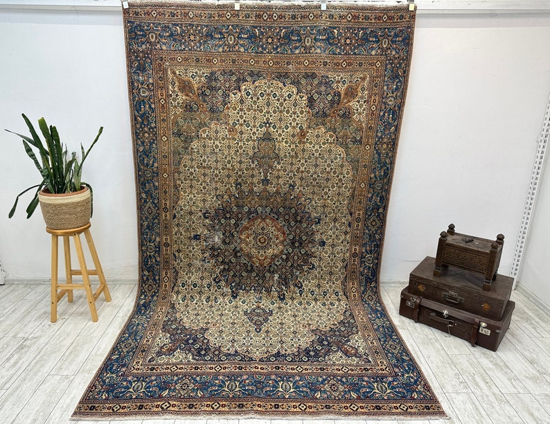 May include: A vintage Persian rug with a cream-colored center and a blue, red, and brown border. The rug has a floral pattern and is in good condition.