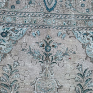 Puede incluir: Una alfombra vintage con fondo beige claro y un patr&oacute;n floral azul y blanco. La alfombra tiene un aspecto descolorido y est&aacute; hecha de un material suave y tejido.