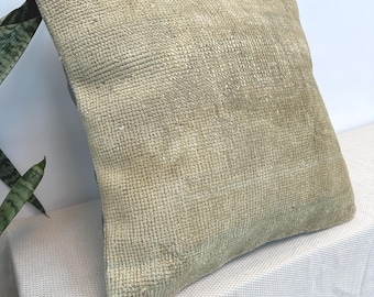 May include: A square throw pillow featuring a textured, woven surface in a muted beige and light tan color palette. The fabric displays a dense, uniform grid-like pattern across the entire front face, creating a tactile appearance.