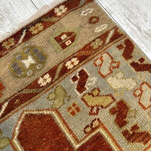 May include: A vintage Turkish rug with a brown, beige, and gray color scheme. The rug has a geometric pattern with a central medallion and a border.