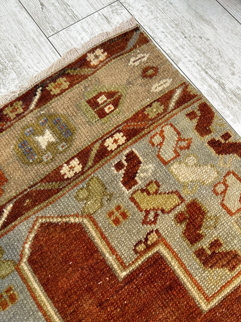 May include: A vintage Turkish rug with a brown, beige, and gray color scheme. The rug has a geometric pattern with a central medallion and a border.