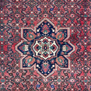 May include: A vintage Persian rug with a red background and a central medallion featuring a floral design in shades of blue, green, and white. The rug has a geometric border with intricate details.