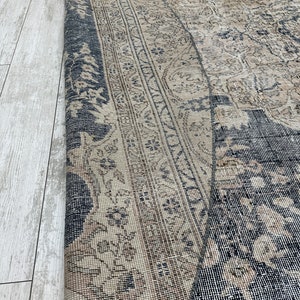 K&ouml;nnte beinhalten: Ein Vintage-Teppich mit einem verblassten, komplizierten Muster in Beige- und Schwarzt&ouml;nen. Der Teppich hat einen abgenutzten, verwitterten Look, der zu seinem Charakter und Charme beitr&auml;gt.