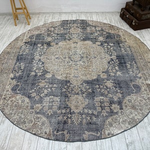 K&ouml;nnte beinhalten: Ein runder, blau- und cremefarbener Teppich mit einem Blumenmuster. Der Teppich hat einen abgenutzten Look und ist aus einem weichen, gewebten Material gefertigt.
