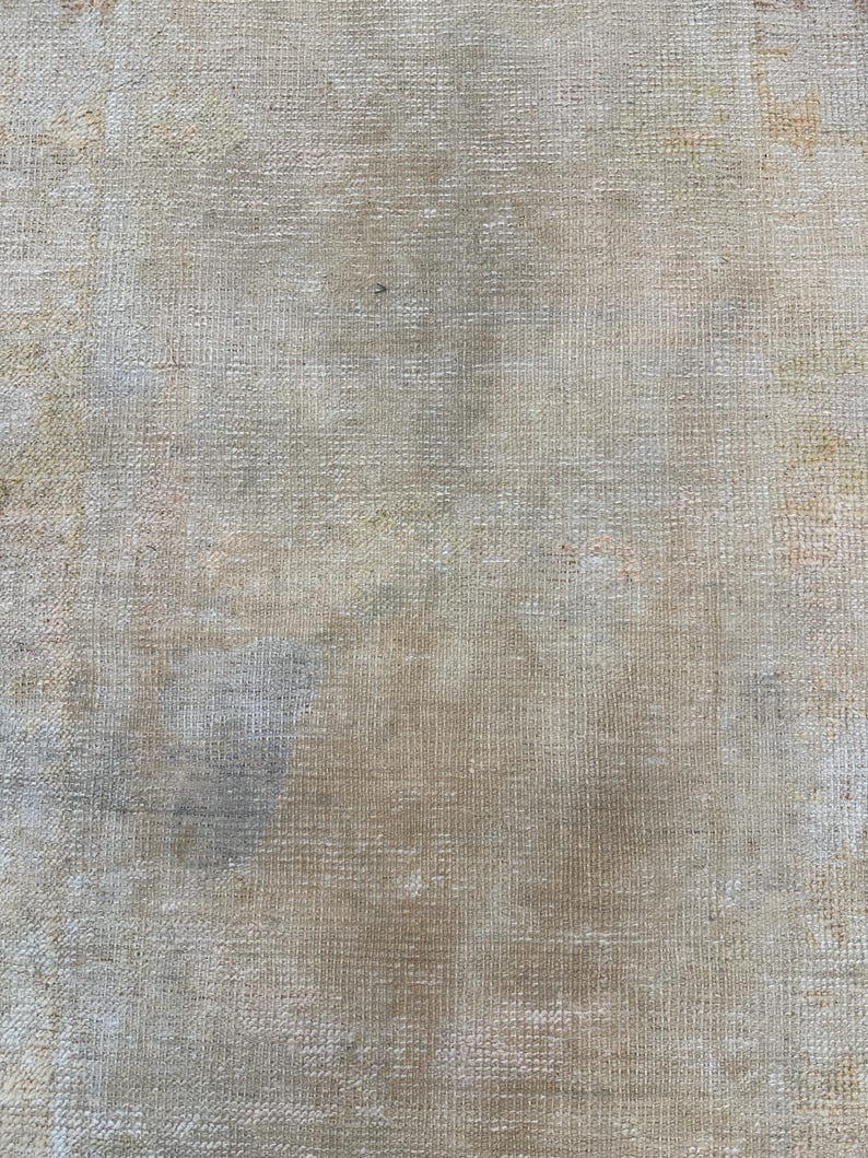 May include: A close-up of a beige canvas texture with a subtle woven pattern. The canvas has a slightly faded appearance with some light brown and gray discoloration.