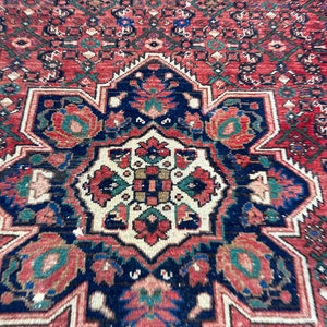May include: A close-up of a red, blue, and green patterned rug with a central medallion. The rug has a traditional Persian design with intricate details.
