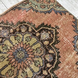 Puede incluir: Una alfombra vintage con un patr&oacute;n floral en tonos de rosa, verde, azul y marr&oacute;n. La alfombra tiene un aspecto desgastado y est&aacute; hecha de lana.