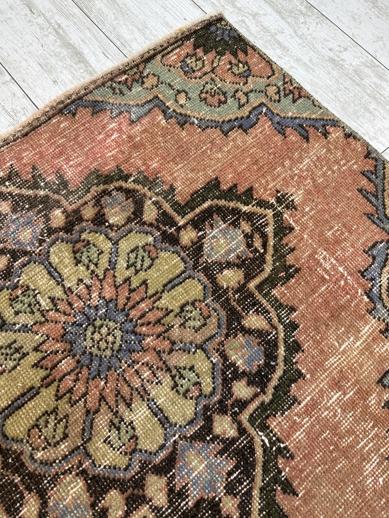 Puede incluir: Una alfombra vintage con un patr&oacute;n floral en tonos de rosa, verde, azul y marr&oacute;n. La alfombra tiene un aspecto desgastado y est&aacute; hecha de lana.