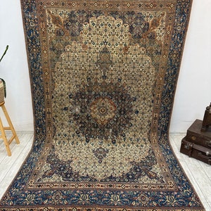 May include: A vintage Persian rug with a blue and cream color scheme. The rug features a central medallion with intricate floral patterns and a border with repeating motifs.