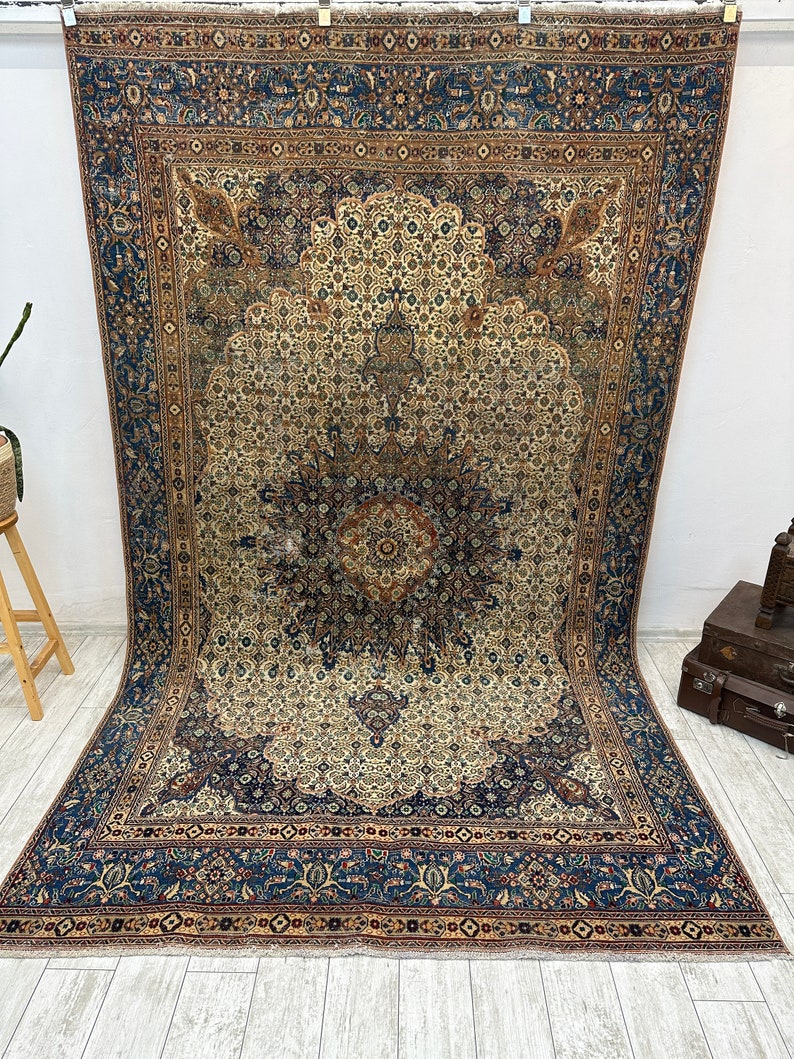 May include: A vintage Persian rug with a blue and cream color scheme. The rug features a central medallion with intricate floral patterns and a border with repeating motifs.