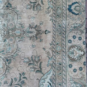 Puede incluir: Una alfombra vintage con fondo beige y un patr&oacute;n floral en tonos azules y marrones. La alfombra tiene un borde con un dise&ntilde;o geom&eacute;trico.