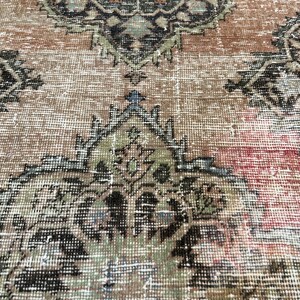 Puede incluir: Primer plano de una alfombra vintage con un patr&oacute;n floral descolorido en tonos marrones, verdes y azules. La alfombra tiene un aspecto desgastado y descolorido, lo que le da un car&aacute;cter &uacute;nico.
