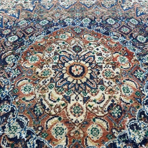May include: A vintage rug with a detailed, intricate pattern in shades of blue, brown, and cream. The rug features a central medallion with a floral design.