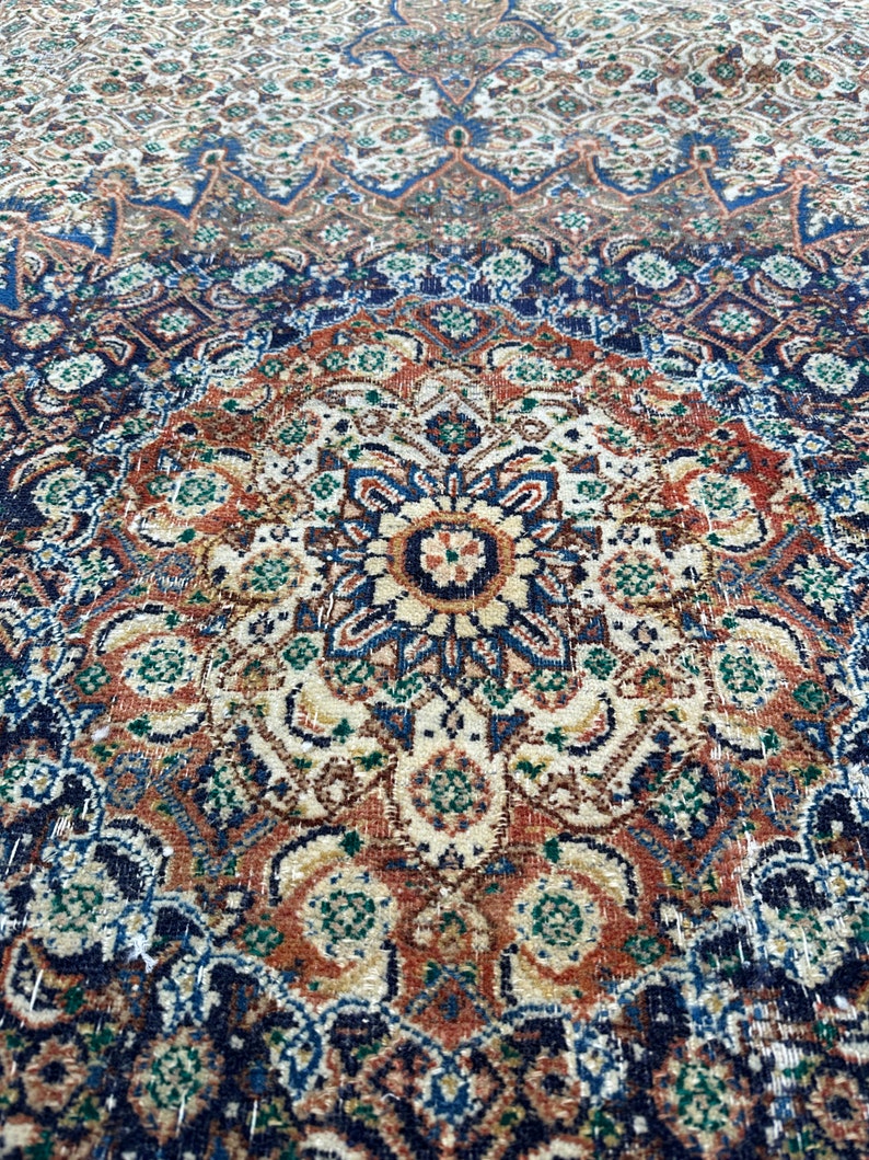 May include: A vintage rug with a detailed, intricate pattern in shades of blue, brown, and cream. The rug features a central medallion with a floral design.