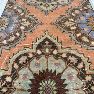 May include: A vintage rug with a faded peach background and intricate floral patterns in shades of brown, green, and blue.