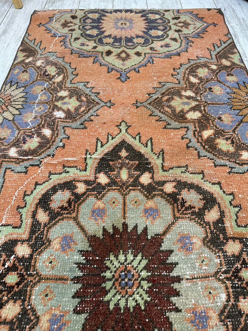 May include: A vintage rug with a faded peach background and intricate floral patterns in shades of brown, green, and blue.