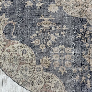 K&ouml;nnte beinhalten: Nahaufnahme eines runden, blauen und beigen Teppichs mit einem floralen Muster. Der Teppich hat einen abgenutzten, Vintage-Look.