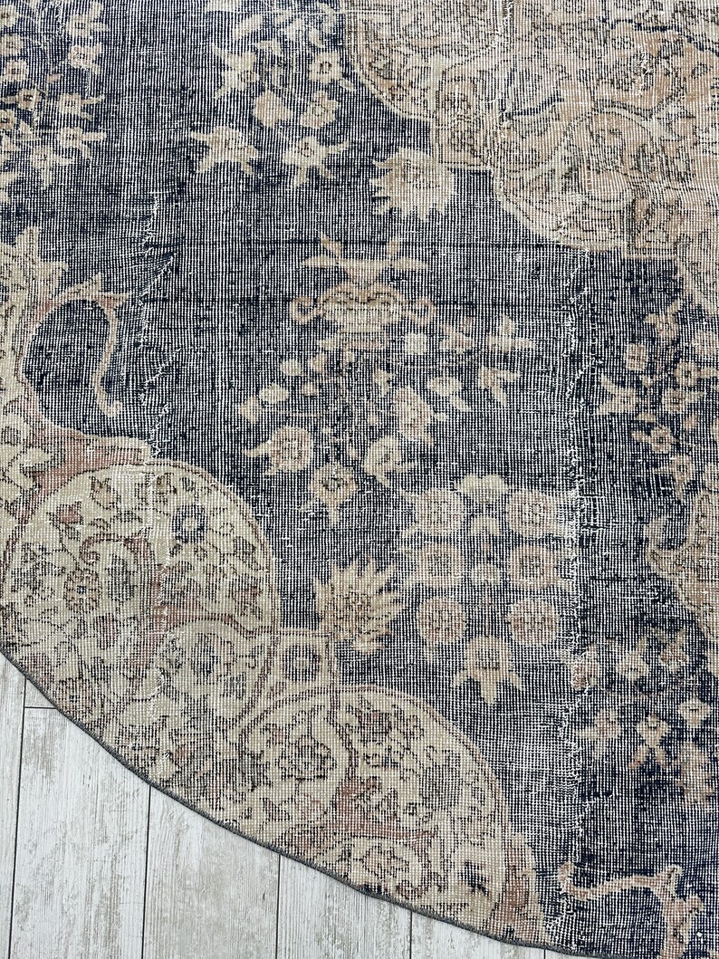 K&ouml;nnte beinhalten: Nahaufnahme eines runden, blauen und beigen Teppichs mit einem floralen Muster. Der Teppich hat einen abgenutzten, Vintage-Look.