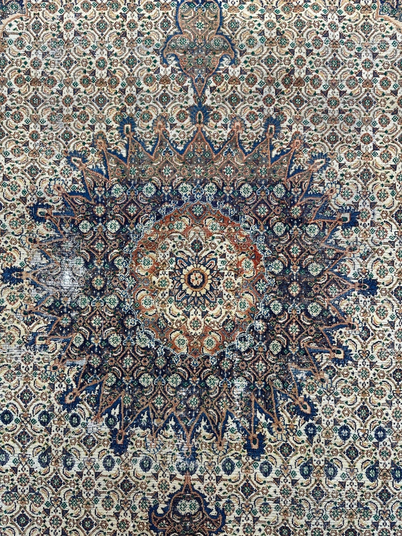 May include: A vintage rug with a blue, brown, and white geometric pattern. The rug has a central medallion with a starburst design.