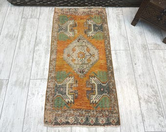 May include: A rectangular area rug featuring a vibrant orange central field with a large, light gray diamond-shaped medallion at the center. The rug displays symmetrical geometric patterns in shades of green, dark gray, and cream, with a detailed border.