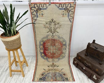 Puede incluir: Una alfombra rectangular vintage con fondo crema y patrones intrincados en rojo, azul y marrón. La alfombra presenta un diseño de medallón central y bordes decorativos, agregando un toque de estilo tradicional.