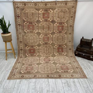 May include: A beige and brown patterned rug with a geometric design. The rug has a border with a repeating pattern.