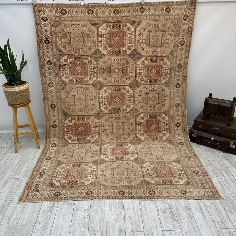 May include: A beige and brown patterned rug with a geometric design. The rug has a border with a repeating pattern.