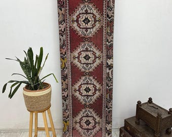 Puede incluir: Una alfombra roja vintage de corredor con un patrón geométrico en tonos de blanco, negro y beige. La alfombra tiene un aspecto desgastado y es perfecta para agregar un toque de estilo bohemio a tu hogar.