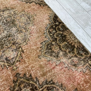 Puede incluir: Una alfombra vintage con un esquema de color rosa y marr&oacute;n descolorido. La alfombra tiene un dise&ntilde;o persa tradicional con intrincados patrones florales.