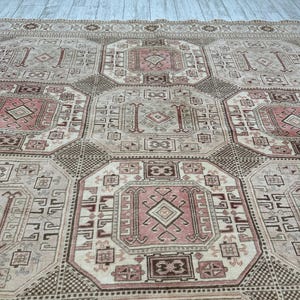 May include: A vintage rug with a geometric pattern in shades of beige, brown, and pink. The rug features a repeating design of squares and diamonds.
