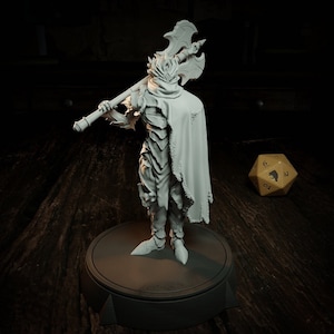 Peut inclure: Figurine grise d'un guerrier en armure, tenant une grande hache à double lame sur son épaule. Le guerrier porte une cape et se tient sur une plateforme ronde. Un dé à dix faces est en arrière-plan.
