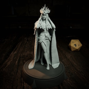 Peut inclure: Une figurine miniature peinte en blanc représentant une femme portant une couronne et une longue robe flottante. La figurine est debout sur une base ronde.