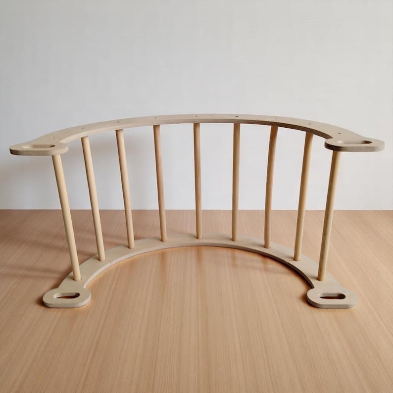 May include: A natural wood-coloured, curved wooden climbing arch with vertical dowels. The arch has a rounded base and two side platforms with holes. The design is simple and modern, suitable for children's play.