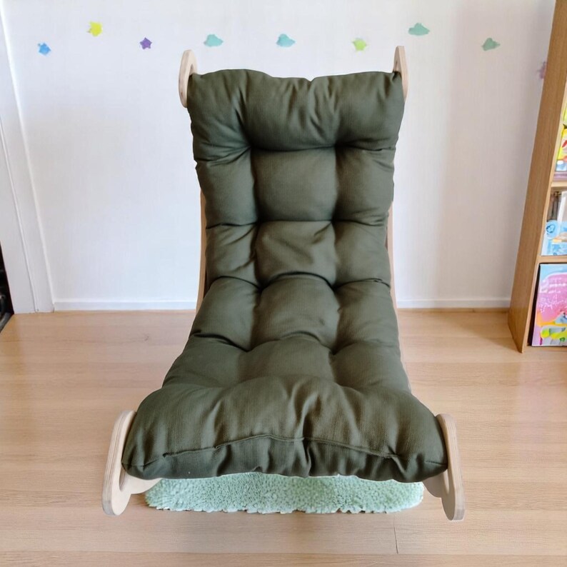 May include: A green cushioned rocking chair with a wooden frame. The chair has a high back and a tufted design on the seat and backrest. The chair is on a small green rug.