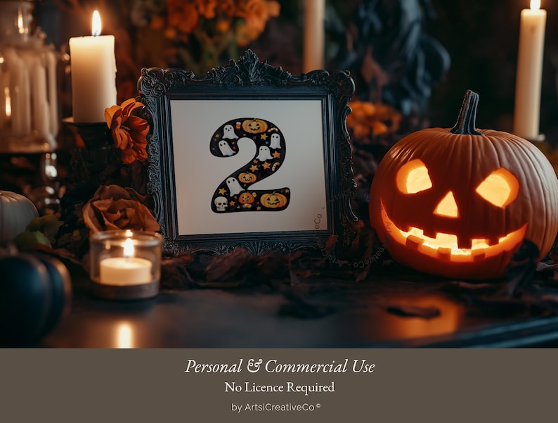 May include: A black framed picture with a white background and the number "2" in black with a Halloween theme. The number is surrounded by ghosts, pumpkins, and stars. The picture is sitting on a table with a lit jack-o'-lantern and candles.